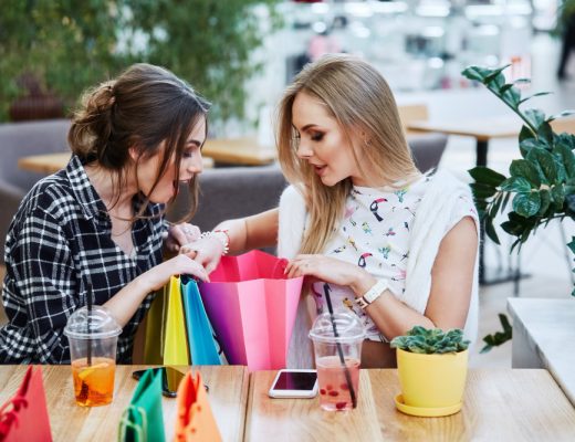 Ein Bild von zwei Frauen, die sich über Einkaufstüten beugen