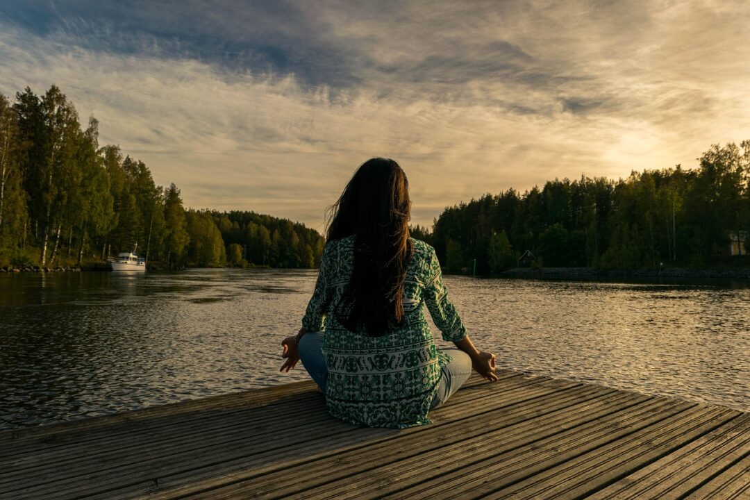 Frau meditiert am Wasser und genießt Ruhe – Darstellung für Work-Life-Balance in Deutschland