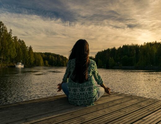 Frau meditiert am Wasser und genießt Ruhe – Darstellung für Work-Life-Balance in Deutschland