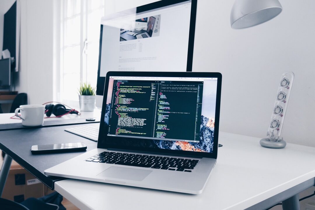 Modernes Büro mit Laptop und Code auf dem Bildschirm – Team bereitet Prozesse für E-Rechnung Pflicht 2025 (XRechnung/ZUGFeRD) vor.