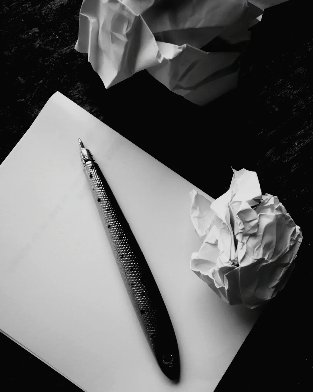 Notizpapier mit Stift und zerknüllten Blättern – symbolisches Bild für das Trauerkarte schreiben.