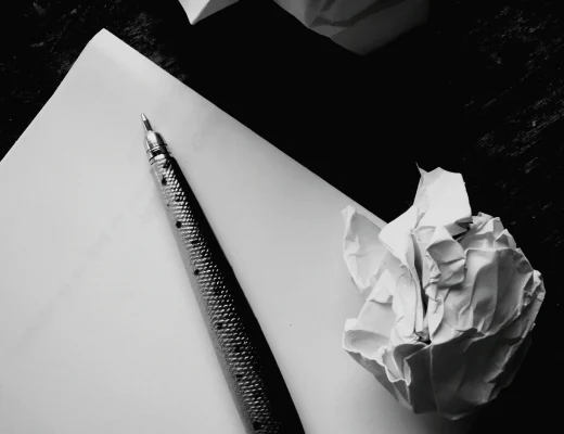 Notizpapier mit Stift und zerknüllten Blättern – symbolisches Bild für das Trauerkarte schreiben.