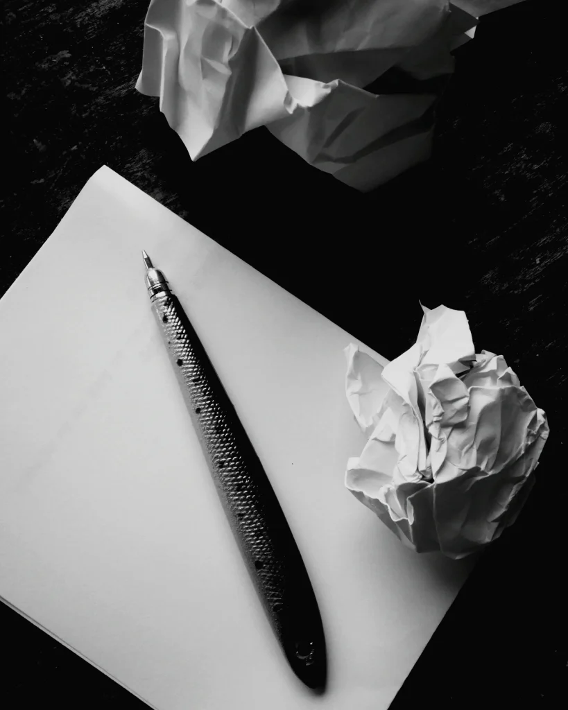 Notizpapier mit Stift und zerknüllten Blättern – symbolisches Bild für das Trauerkarte schreiben.