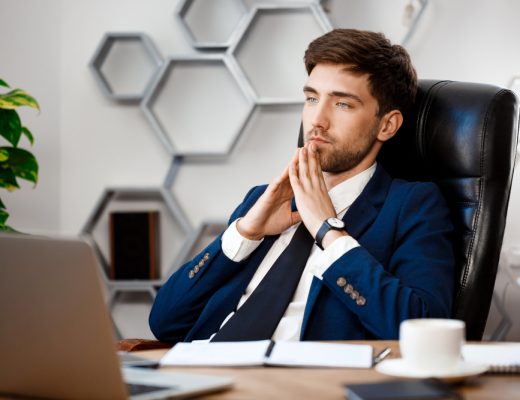 Ein Mann in einem Büro, der am Laptop arbeitet und nachdenkt.
